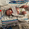 newborn, baby, infant, hospital, incubator, neonatal_care, medical_equipment, pacifier, diaper, blanket, heart, sleeping, face, legs, feet, tubes, wires, monitor, bedsheet, portrait