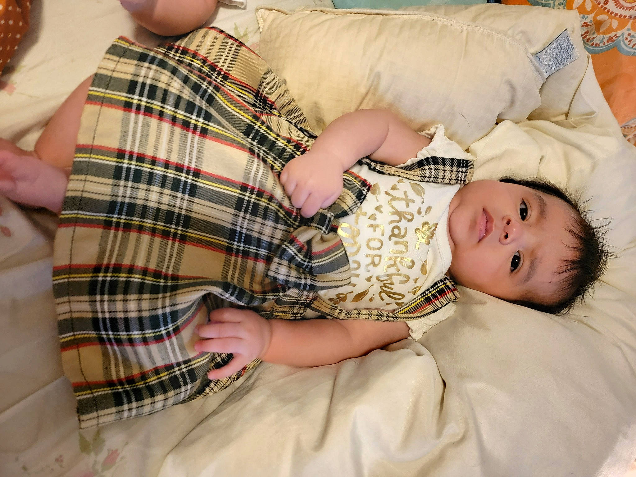 Leilani is registered to the contest to win money with this photo: abdomen, baby, baby_toddler_clothing, bedding, child, comfort, hand, happy, human_leg, lap, linens, nail, pattern, person, plaid, room, sitting, tartan, textile, thigh