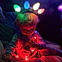 toddler, child, lights, fairy_lights, christmas_lights, holiday, cozy, couch, blanket, pajamas, indoor, night, colorful, glowing, face, curly_hair, hands, sitting, soft_light, warm