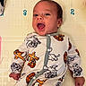 baby, infant, child, portrait, smiling, happy, lying_down, onesie, clothing, cartoon, animal_print, tiger, bear, changing_mat, nursery, indoor, closeup, face, playful, family_photo