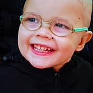 Sylvain Junior participe au concours pour gagner de l'argent avec cette photo : black_clothing, blond_hair, child, close_up, cute, expression, eyewear, face, glasses, happy, head, indoor, joy, light_skin, person, portrait, smiling, teeth, young, zipper