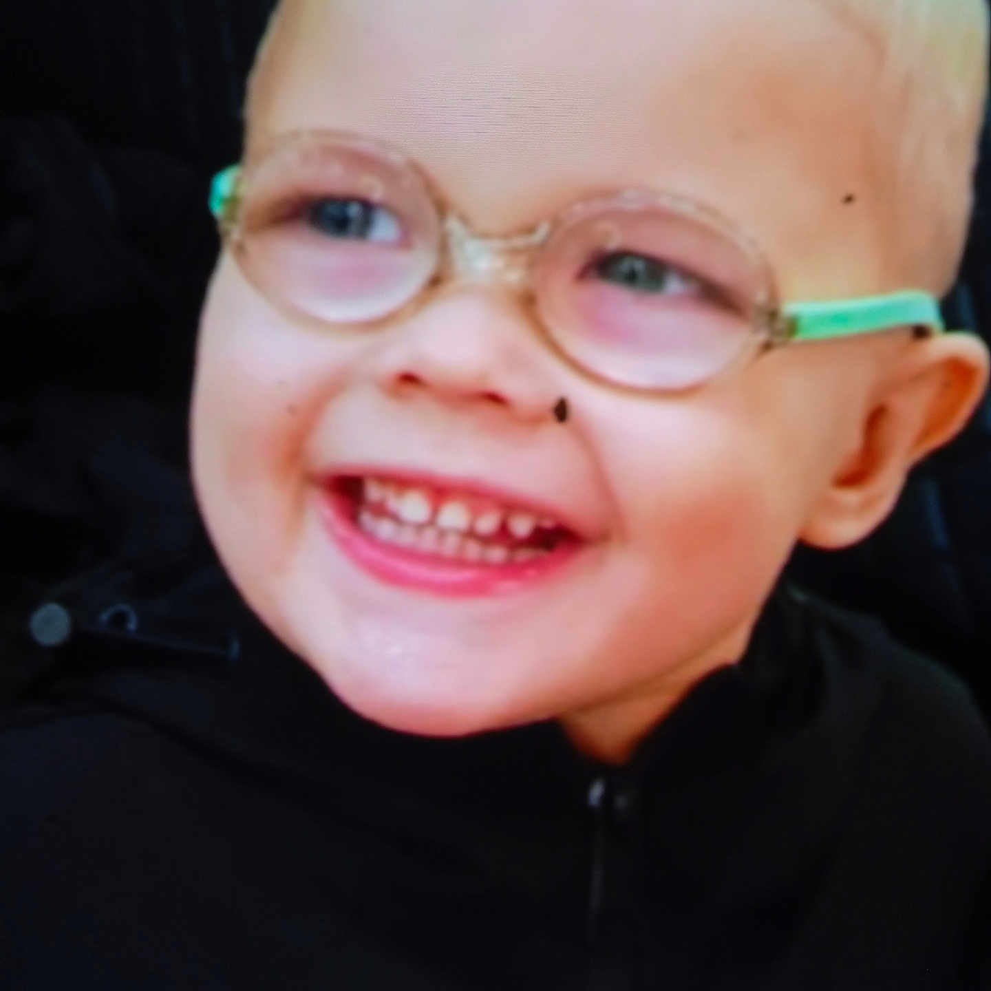 Sylvain Junior participe au concours pour gagner de l'argent avec cette photo : black_clothing, blond_hair, child, close_up, cute, expression, eyewear, face, glasses, happy, head, indoor, joy, light_skin, person, portrait, smiling, teeth, young, zipper