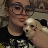 woman, glasses, puppy, dog, indoor, portrait, selfie, animal, pet, casual, smile, cute, young_adult, face, hand, holding, tshirt, hair, picture, background