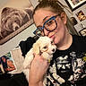 person, puppy, dog, glasses, indoor, portrait, smile, cuddle, animal, tshirt, photograph, wall_art, bear, family_photo, bedroom, decor, hair_tied, casual_clothing, hand, cute
