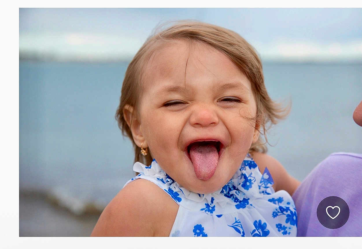 Kya joined the competition — help win amazing prizes! child, girl, tongue_out, smiling, blue_flower_dress, earrings, outdoor, water, sea, shore, playful, happy, portrait, person, summer, casual_clothing, cute, fun, face, hair