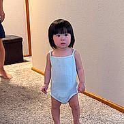 Esther Pham joined the competition — help win amazing prizes! toddler, child, indoor, carpet, barefoot, onesie, wall, wooden_baseboard, person, short_hair, standing, neutral_expression, home_interior, adult_partial, floor, light_blue_clothing, young_child, asian_child, curious, small_person