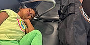 Amara is registered to the contest to win money with this photo: child, waiting_area, airport_chairs, casual_clothing, green_pants, yellow_shirt, black_bag, prime_label, seated_person, resting, indoor, metal_armrest, white_shoes, thoughtful, waiting, public_space, travel, luggage, relaxed, people