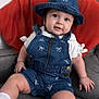 baby, denim, overalls, hat, smile, couch, orange_pillow, white_shoes, white_socks, indoor, child, cute, portrait, happy, seated, clothing, face, person, infant, home