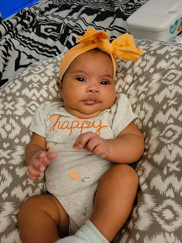 Brooklynn is registered to the contest to win money with this photo: baby, baby_toddler_clothing, cap, cheek, child, comfort, facial_expression, fashion_accessory, hat, headgear, human_leg, linens, pattern, person, product, skin, smile, textile, thigh, toddler