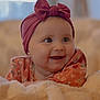 baby, blanket, bow, child, closeup, cozy, cute, expression, face, floral_clothing, happy, headband, indoors, infant, person, portrait, smiling, soft_light, toddler, warm_colors