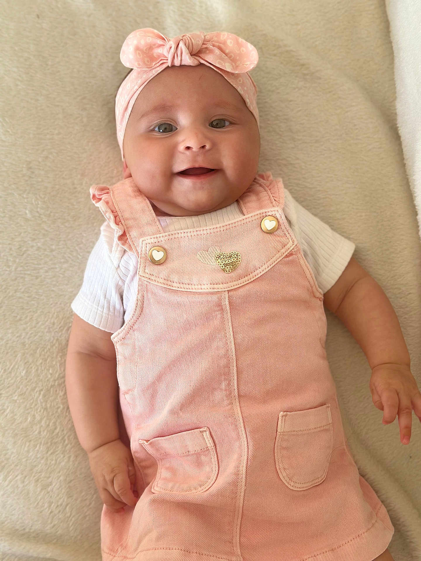 Zélie a rejoint le concours — aidez-le/la à gagner de superbes lots ! baby, infant, smiling, headband, pink_dress, cute, child, happy, portrait, indoors, soft_blanket, lying_down, chubby_cheeks, closeup, young_child, adorable, fashion, headwear, warm_colors, person