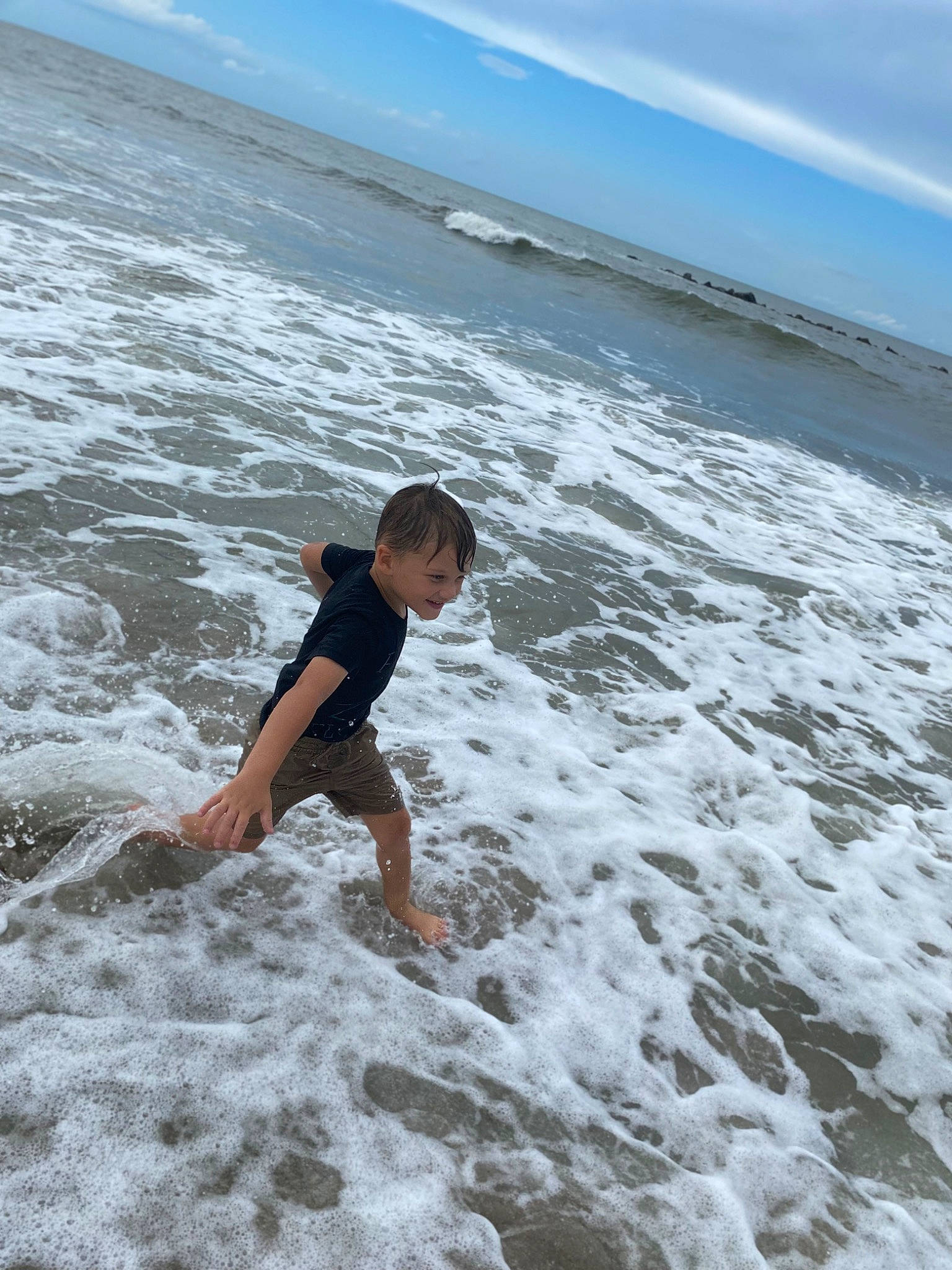 Curtis is registered to the contest to win money with this photo: barefoot, beach, cloud, coastal_and_oceanic_landforms, flash_photography, fun, happy, horizon, joy, leisure, people_in_nature, people_on_beach, person, recreation, sand, shore, shorts, sky, water, wave