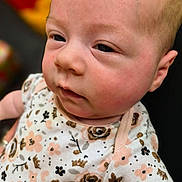 Phoenix joined the competition — help win amazing prizes! baby, infant, face, closeup, onesie, floral_pattern, soft_skin, cute, child, portrait, young, newborn, clothing, baby_girl, expression, pink, gold, black, background_blur, indoor