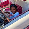 Rhyli is registered to the contest to win money with this photo: blue_hair_clips, car, child, daylight, dress, fun, girl, happy, interior, people, pink_seats, portrait, seat, smile, steering_wheel, transportation, vehicle, vintage_car, white_seats, window