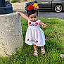 toddler, child, girl, white_dress, flower_headband, grass, outdoor, concrete_pillar, cars, sidewalk, sandals, greenery, cute, balancing, daylight, person, nature, small_flowers, building, urban