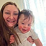 Jenna is registered to the contest to win money with this photo: woman, child, toddler, smile, happy, indoor, curtains, natural_light, face, person, holding, rosy_cheeks, long_hair, white_shirt, home, portrait, family, closeup, candid, affection