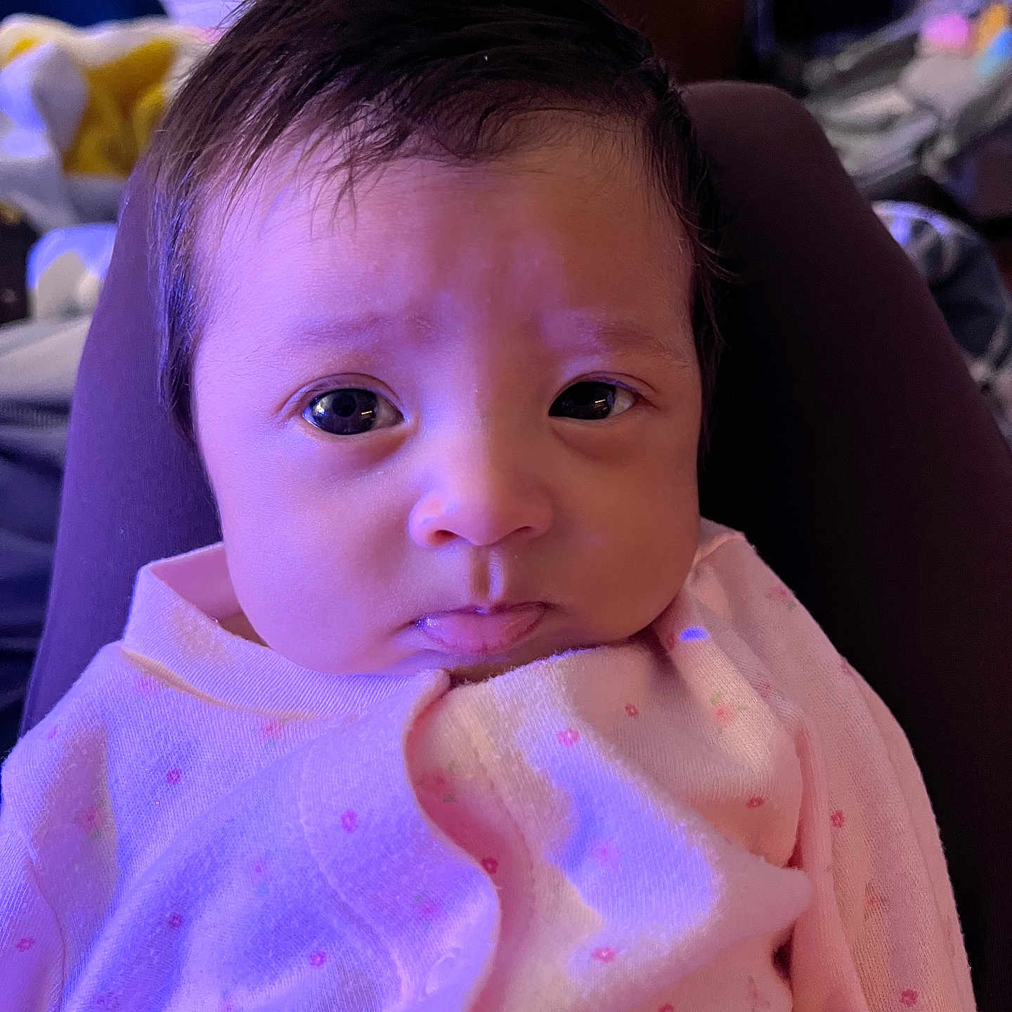 Eliana joined the competition — help win amazing prizes! baby, infant, child, portrait, face, eyes, hair, serious, sitting, pink_clothing, blanket, chair, indoor, close_up, looking_at_camera, soft_lighting, purple_lighting, cozy, photography, adorable