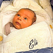 Eli joined the competition — help win amazing prizes! baby, infant, blanket, knitwear, cozy, face, portrait, sleeping_bag, child, cute, warm, indoor, newborn, expression, soft_texture, clothing, bundle, head, comfort, looking_up