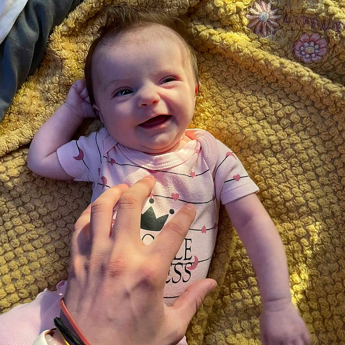 Olivia is registered to the contest to win money with this photo: accessories, baby, blanket, bodypart, bracelet, clothing, face, finger, furniture, hand, happy, head, jewelry, newborn, person, photography, portrait, quilt, ring, t_shirt