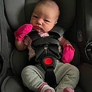 Aurelia is registered to the contest to win money with this photo: baby, infant, car_seat, graco, pink_mittens, clothing, socks, straps, seat_belt, face, person, child, newborn, cute, indoor, portrait, serious_expression, baby_girl, sitting, safety