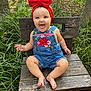 baby, child, red_bow, denim_overalls, smiling, tongue_out, wooden_chair, outdoor, greenery, grass, happy, cute, infant, nature, portrait, sitting, headband, playful, person, summer