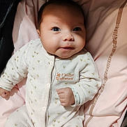 Adélina a rejoint le concours — aidez-le/la à gagner de superbes lots ! baby, infant, onesie, white_clothing, golden_hearts, pink_blanket, lying_down, face, smile, cute, child, newborn, soft_fabric, indoor, portrait, closeup, adorable, baby_clothes, small_hands, sleepwear