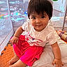 toddler, child, baby, smiling, sitting, playpen, toy, cushion, clothing, indoors, cute, happy, person, face, short_hair, pink_skirt, white_tshirt, floor_mat, play_area, young_child