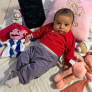 Névya a rejoint le concours — aidez-le/la à gagner de superbes lots ! baby, child, plush_toy, pillow, blanket, knitted, floor_tile, blackboard, writing, red_clothing, purple_pants, sock, cute, indoors, portrait, smiling, toy, soft_toy, embroidery, relaxing