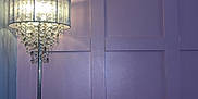 Meeko is registered to the contest to win money with this photo: indoor, lamp, floor_lamp, chandelier, light, purple_wall, panel_wall, couch, sofa, gray_cat, kitten, pet, furniture, cozy, home, curious, animal, domestic_cat, resting, soft_light