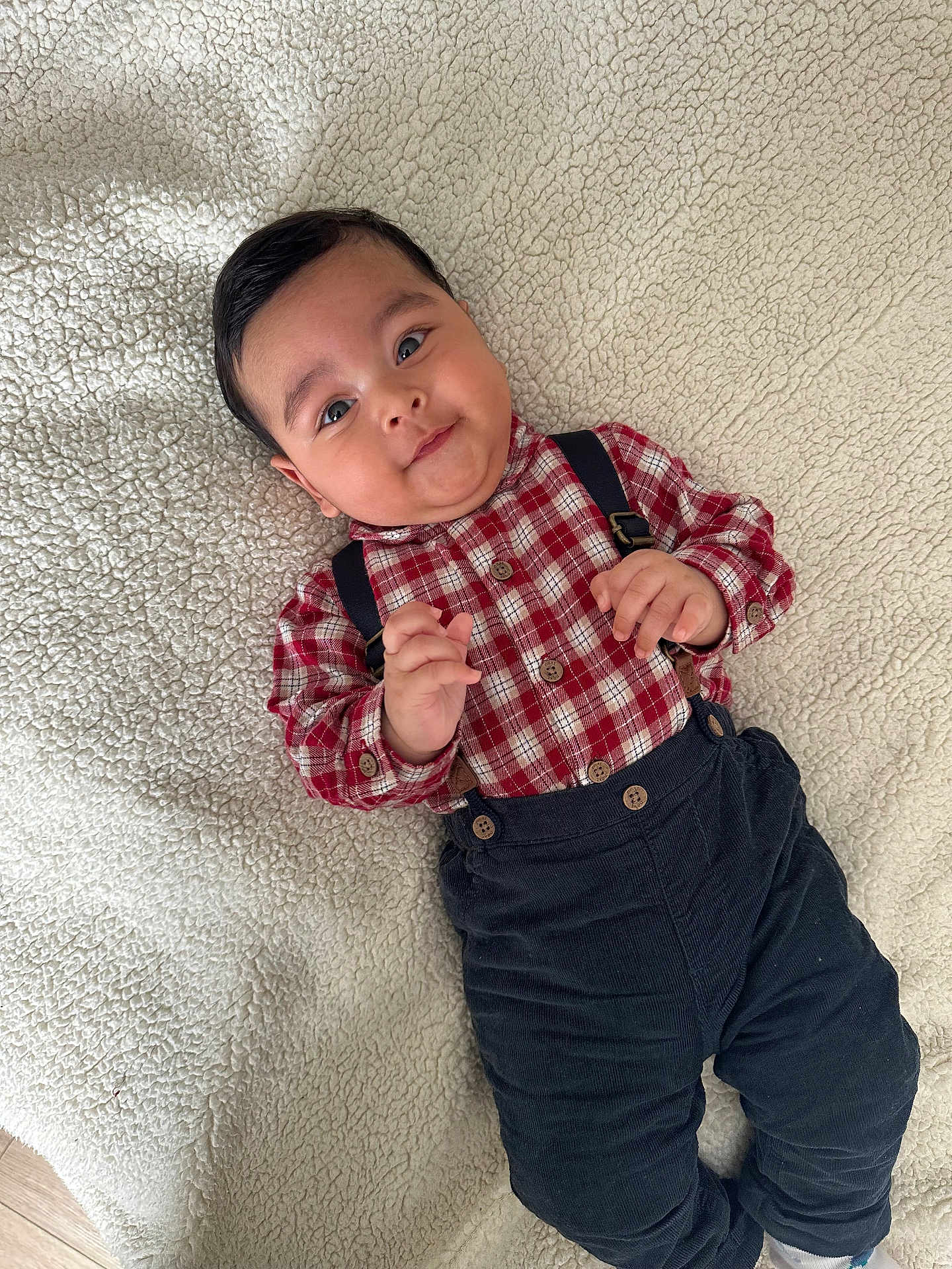 Zain joined the competition — help win amazing prizes! baby, child, infant, plaid_shirt, suspenders, pants, lying_down, blanket, cozy, cute, smiling, indoor, face, hands, feet, young_child, portrait, casual_clothing, fabric, happy