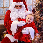 Aëlia participe au concours pour gagner de l'argent avec cette photo : baby, celebration, child, christmas, christmas_tree, decorations, festive, glasses, gloves, happy, holiday, indoor, person, portrait, presents, red_dress, santa_claus, seasonal, smiling, white_beard