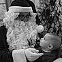 baby, beard, black_and_white, child, christmas, costume, curious, decorations, face, festive, flowers, glasses, gloves, holiday, indoor, looking_up, person, portrait, santa_claus, snowflakes