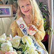 Myla a rejoint le concours — aidez-le/la à gagner de superbes lots ! accessories, blonde, child, face, female, flower, flowerarrangement, flowerbouquet, girl, hair, head, jewelry, lady, necklace, person, photoframe, plant, pottedplant, rose, sash