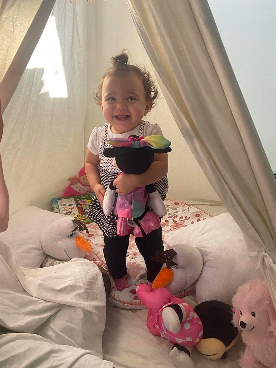 Mackenzie is registered to the contest to win money with this photo: baby_toddler_clothing, child, comfort, curtain, fun, hairstyle, hand, happy, human_leg, joy, knee, mammal, mouth, person, pillow, pink, purple, skin, smile, textile
