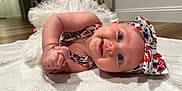 Adelaide is registered to the contest to win money with this photo: baby, infant, smiling, headband, bow, clothing, blanket, floor, indoor, happy, cute, child, portrait, toddler, person, face, skin, blue_eyes, cheerful, laying