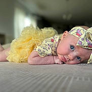 Adelaide joined the competition — help win amazing prizes! baby, infant, child, yellow_dress, headband, bow, blue_eyes, lying_down, soft_surface, indoors, close_up, portrait, cute, adorable, curious, frilly, clothing, person, human, face