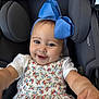 baby, child, smiling, blue_bow, floral_dress, car_seat, happy, cute, infant, portrait, closeup, young_child, clothing, headwear, person, seat, black_background, reaching_hand, indoors, baby_girl