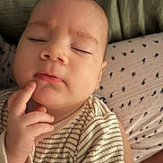 Théo participe au concours pour gagner de l'argent avec cette photo : baby, infant, face, hand, closed_eyes, striped_clothing, giraffe_patch, cushion, patterned_textile, skin, cute, sleepy, resting, portrait, child, person, soft_light, indoors, cozy, thoughtful