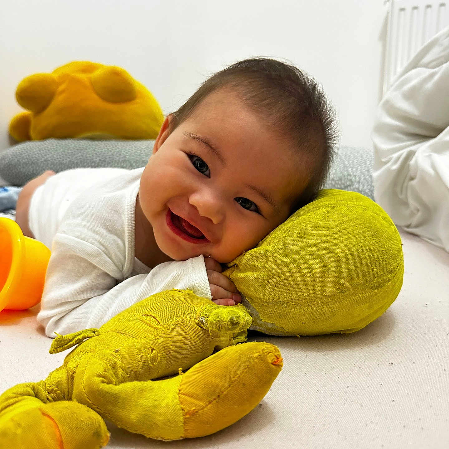 Keapatini a rejoint le concours — aidez-le/la à gagner de superbes lots ! baby, child, comfort, cute, fabric, face, hand, happy, indoor, infant, lying_down, pillow, playtime, plush, radiator, smiling, soft_toy, stuffed_toy, white_clothing, yellow_toy