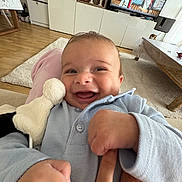 Zayn participe au concours pour gagner de l'argent avec cette photo : baby, smiling, happy, infant, plush_toy, hand, finger, living_room, television, animation, floor, carpet, furniture, blue_clothing, person, indoor, closeup, cute, joy, child
