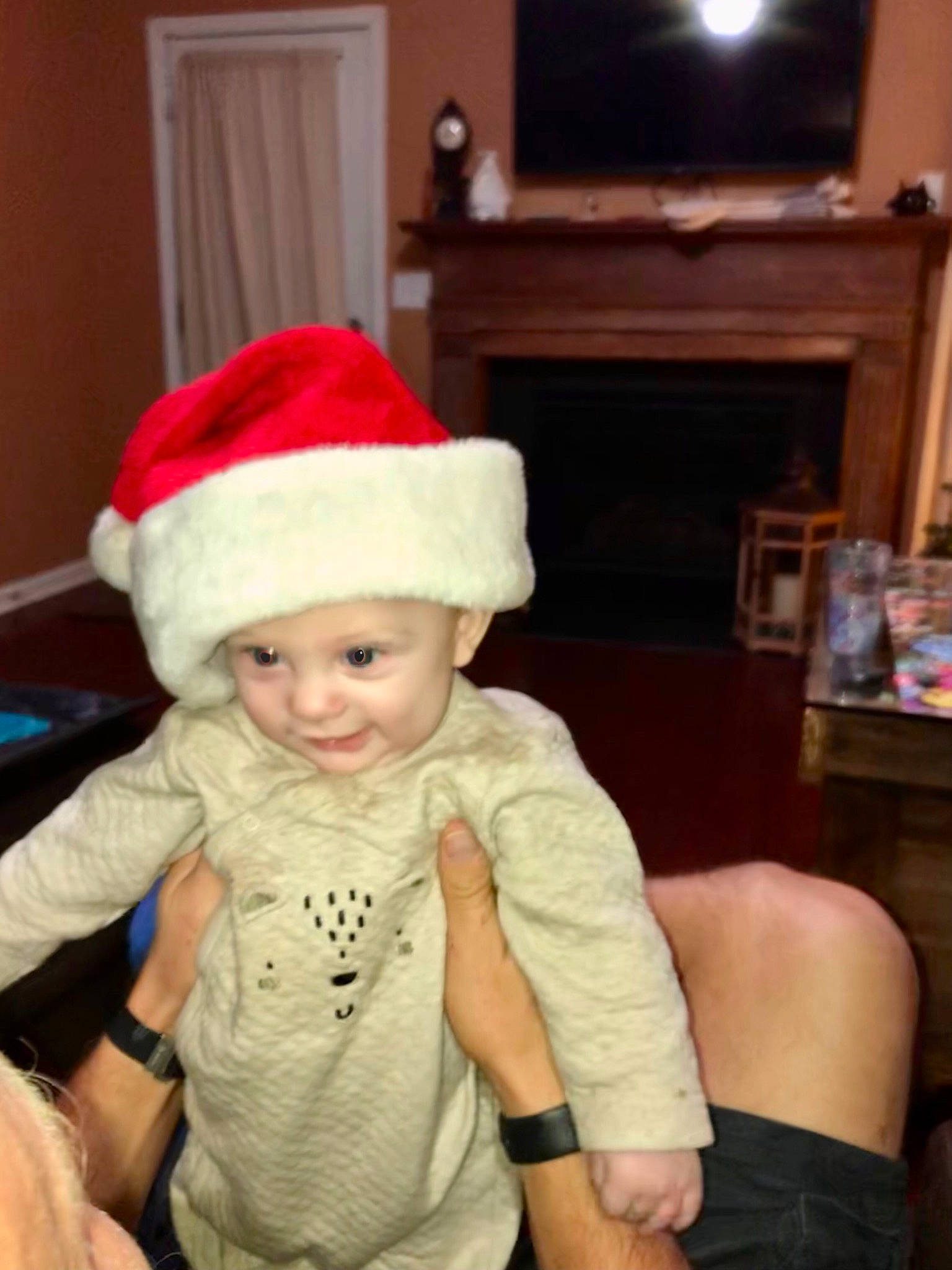 Corey is registered to the contest to win money with this photo: baby, baby_toddler_clothing, cap, child, christmas, christmas_eve, costume_hat, event, fun, happy, hat, headgear, headwear, holiday, lap, living_room, person, room, santa_claus, smile