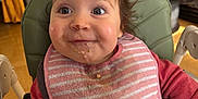 Mia participe au concours pour gagner de l'argent avec cette photo : baby, bib, blue_eyes, brown_hair, child, closeup, face, feeding, food, hands, highchair, indoor, living_room, meal, messy, pillow, portrait, smile, sofa, wooden_floor