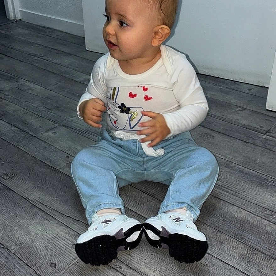 Masha participe au concours pour gagner de l'argent avec cette photo : baby, casual_clothing, child, curious, cute, floor, flooring, footwear, human, indoor, jeans, person, portrait, sitting, small_child, sneakers, toddler, white_shirt, wooden_floor, young_child