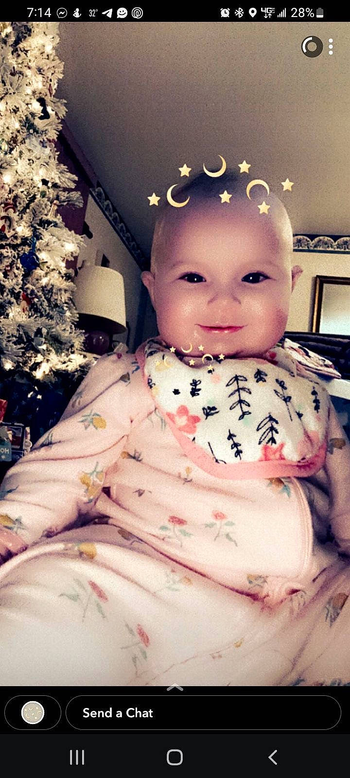 Khloe is registered to the contest to win money with this photo: baby, baby_toddler_clothing, cheek, chest, child, christmas_tree, event, eye, fun, happy, head, headpiece, pattern, person, pink, room, sitting, skin, sleeve, smile