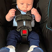 Kolsen is registered to the contest to win money with this photo: baby, car_seat, infant, child, seatbelt, clothing, footwear, blue_pants, white_shoes, black_car_seat, safety_harness, young_child, indoor, portrait, cute, serious_expression, small_hands, head, face, person