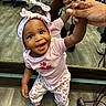 adult_hand, baby, cables, child, cute, floor, floral_pattern, happy, headband, holding_hands, indoor, mirror, person, pink_clothing, portrait, reflection, smiling, socks, toddler, wooden_floor