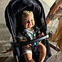 Sandro participe au concours pour gagner de l'argent avec cette photo : baby, stroller, child, smile, blue_eyes, pacifier, night, outdoor, person, clothing, shorts, seatbelt, toy, curly_hair, hand, foot, sidewalk, adult, legs, light