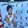 Santino joined the competition — help win amazing prizes! baby, child, mickey_mouse, onesie, smiling, couch, blanket, milestone_blanket, numbers, circled_number, indoor, happy, person, clothing, face, hair, infant, seated, text, furniture