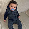 baby, blue, casual, child, clothing, comfort, couch, curious, face, home, hoodie, indoor, infant, pacifier, pants, person, portrait, seated, socks, striped
