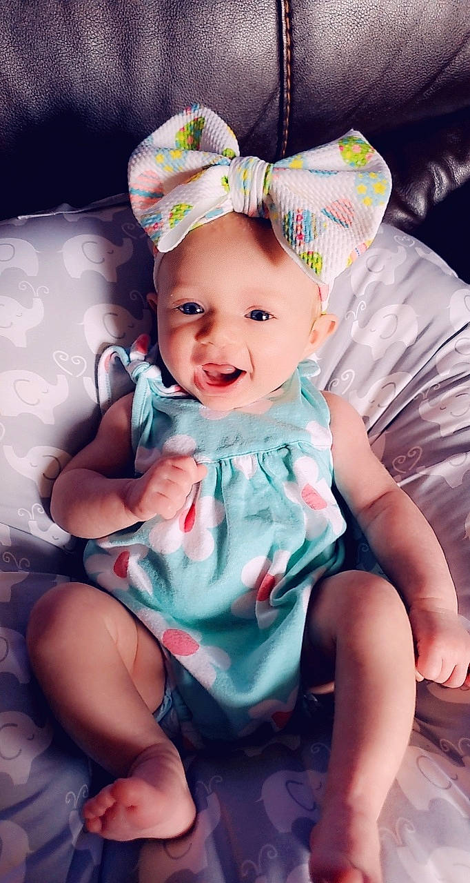 Daniela is registered to the contest to win money with this photo: baby, baby_toddler_clothing, cap, cheek, comfort, dress, eye, face, finger, flash_photography, happy, head, headgear, headwear, iris, person, pink, product, purple, skin